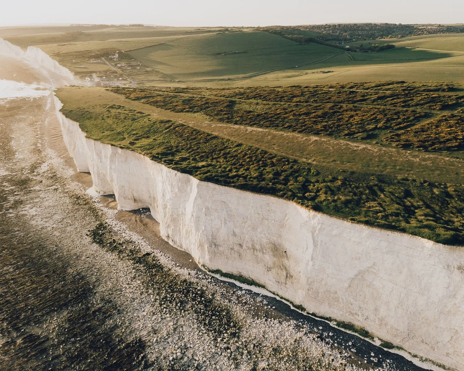 White chalk cliffs below green downland, the same seam of chalk that runs under the vineyard