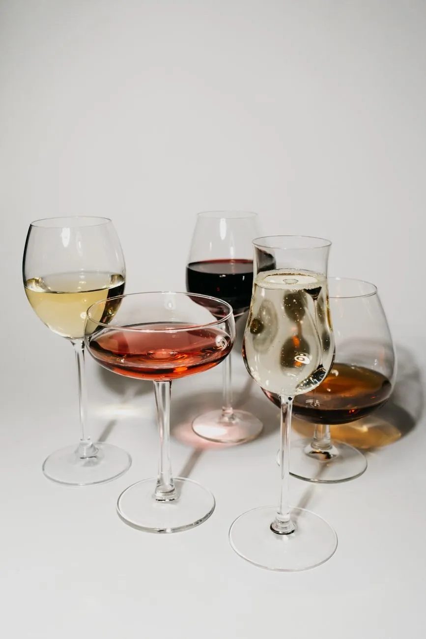 Five glasses of sparkling, white, rosé, red and fortified wine on a pale table