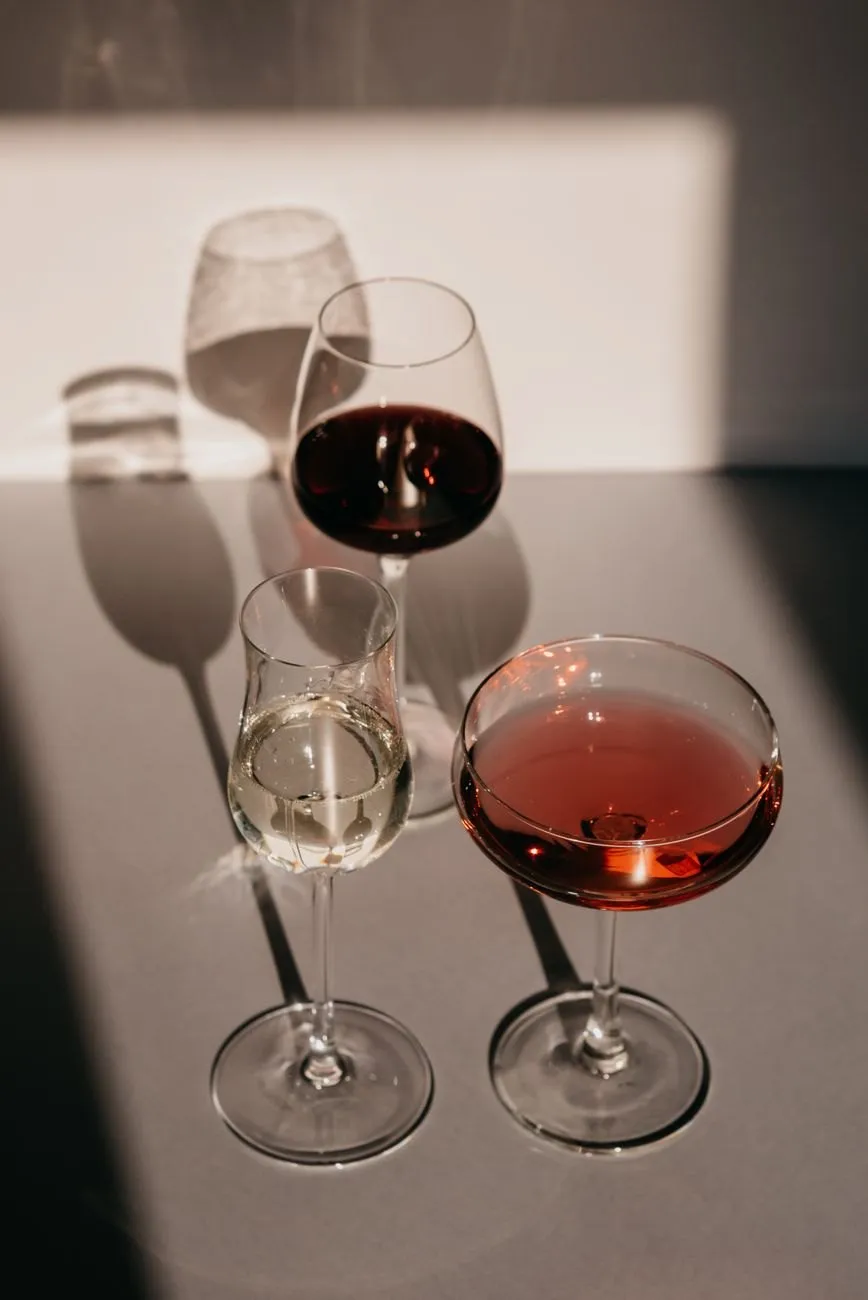 Glasses of red, white and rosé wine casting shadows across a table